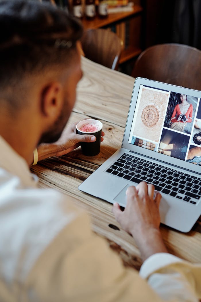 about-01 Man focused on work on laptop with artistic images and coffee in a cozy setting.